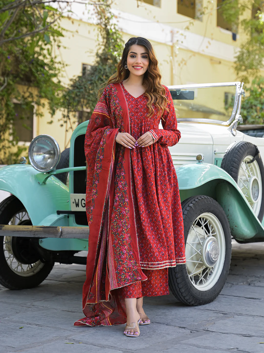 Red Anarkali kurta trouser set with dupatta styled elegantly next to a vintage car